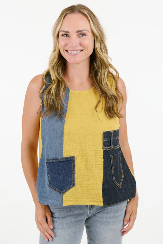 A person wearing the Mirabella Tank by Shannon Passero, expertly crafted from natural cotton fibers featuring yellow and denim patches with two pockets, smiles against a plain background.