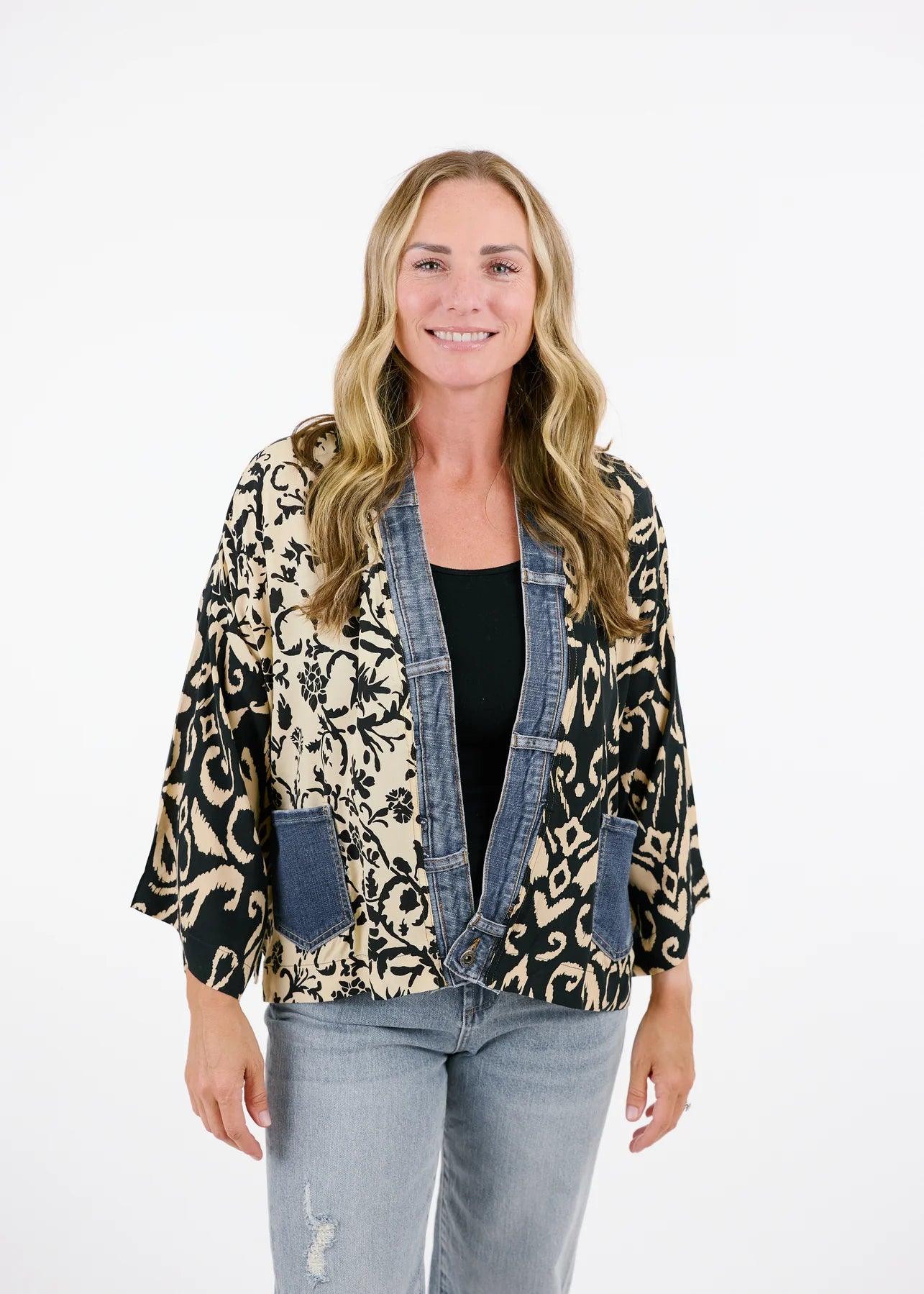 A person wearing the Karol Cardigan by Shannon Passero and vintage upcycled denim stands smiling against a plain background.