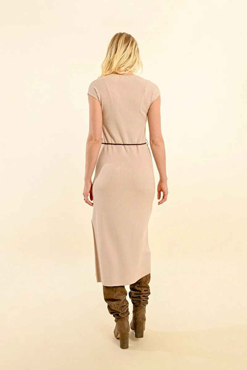 A person wearing the Molly Bracken Short Sleeve Ribbed Dress with Side Slit in beige, paired with a braided black belt and knee-high brown boots, stands against a light background.