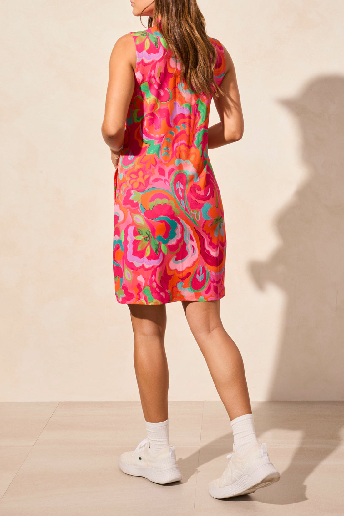 Against a light background, a person stylishly wears the Tribal PERFORMANCE SPORT DRESS, featuring a sleeveless design with an elegant floral pattern, exuding sophistication.