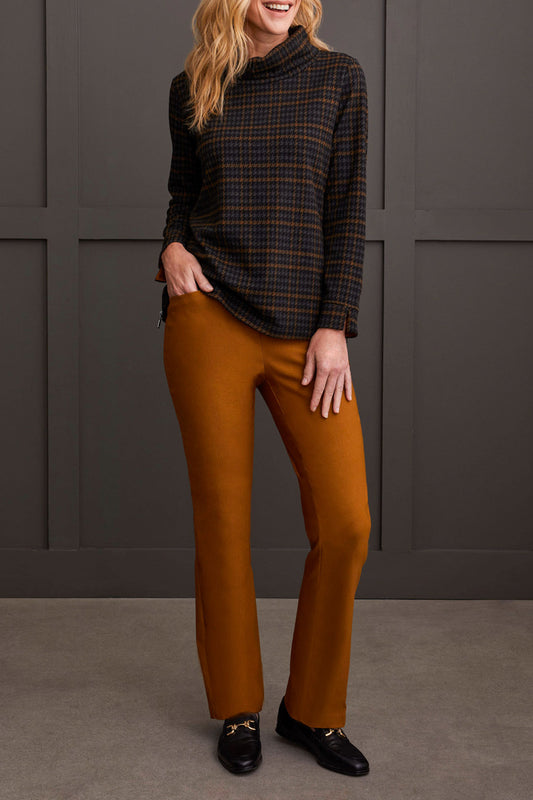 The person is wearing a chic cowl neck top with a side zipper by Tribal, paired with brown pants, standing comfortably in front of a gray paneled wall.