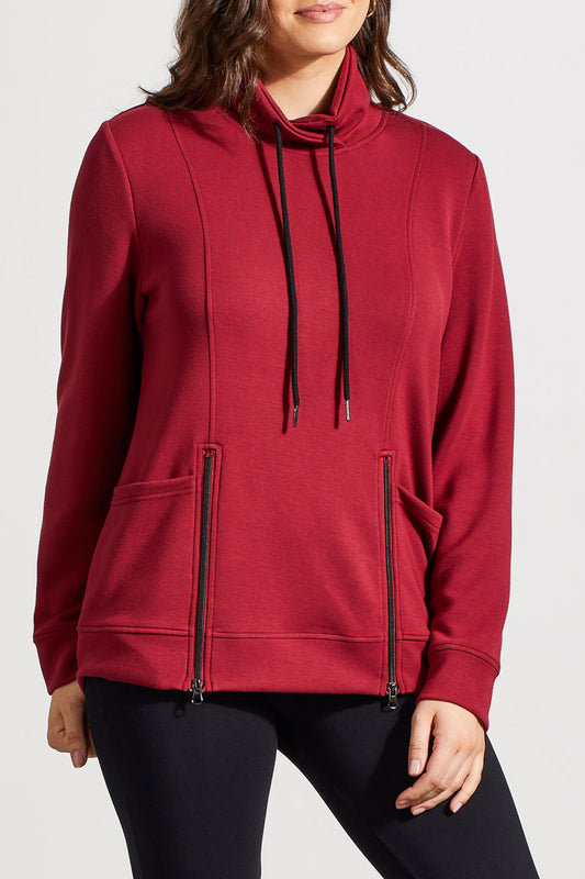 Individual dressed in a red Funnel Neck Top with Pockets by Tribal, featuring drawstrings and crafted from high-quality material, complemented by black pants.