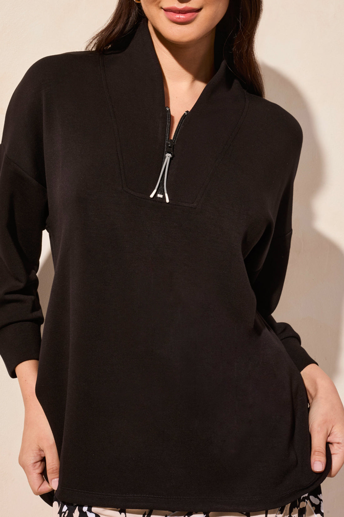 A person wears Tribal's 3/4 Sleeve Top with Zipper, ideal for workouts with its half-zip, relaxed fit design. Their hands rest casually at their sides.