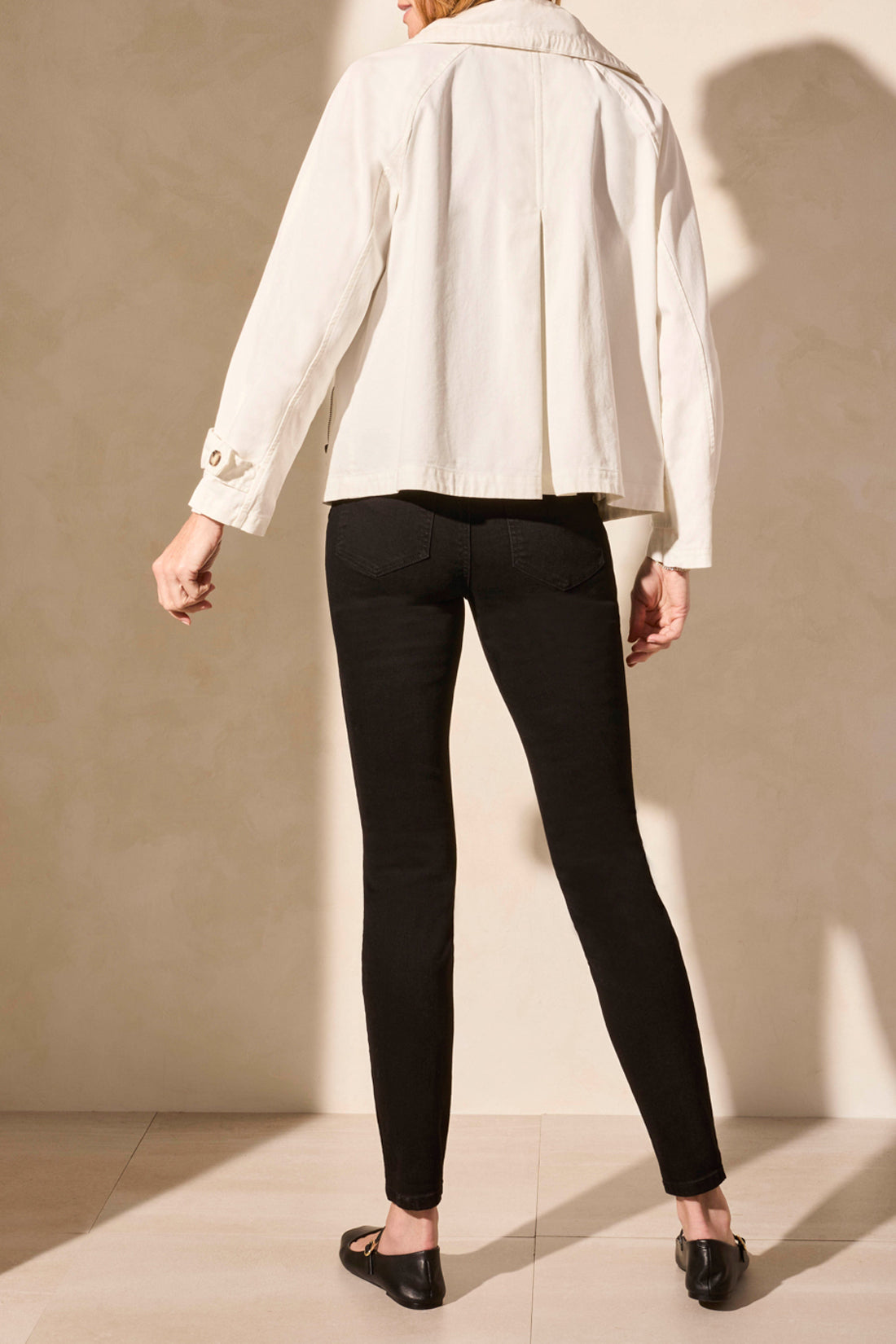 A woman models the Tribal's LONG SLEEVE BUTTON COAT in white, showcasing a cute style paired with a black top and pants against a plain backdrop.