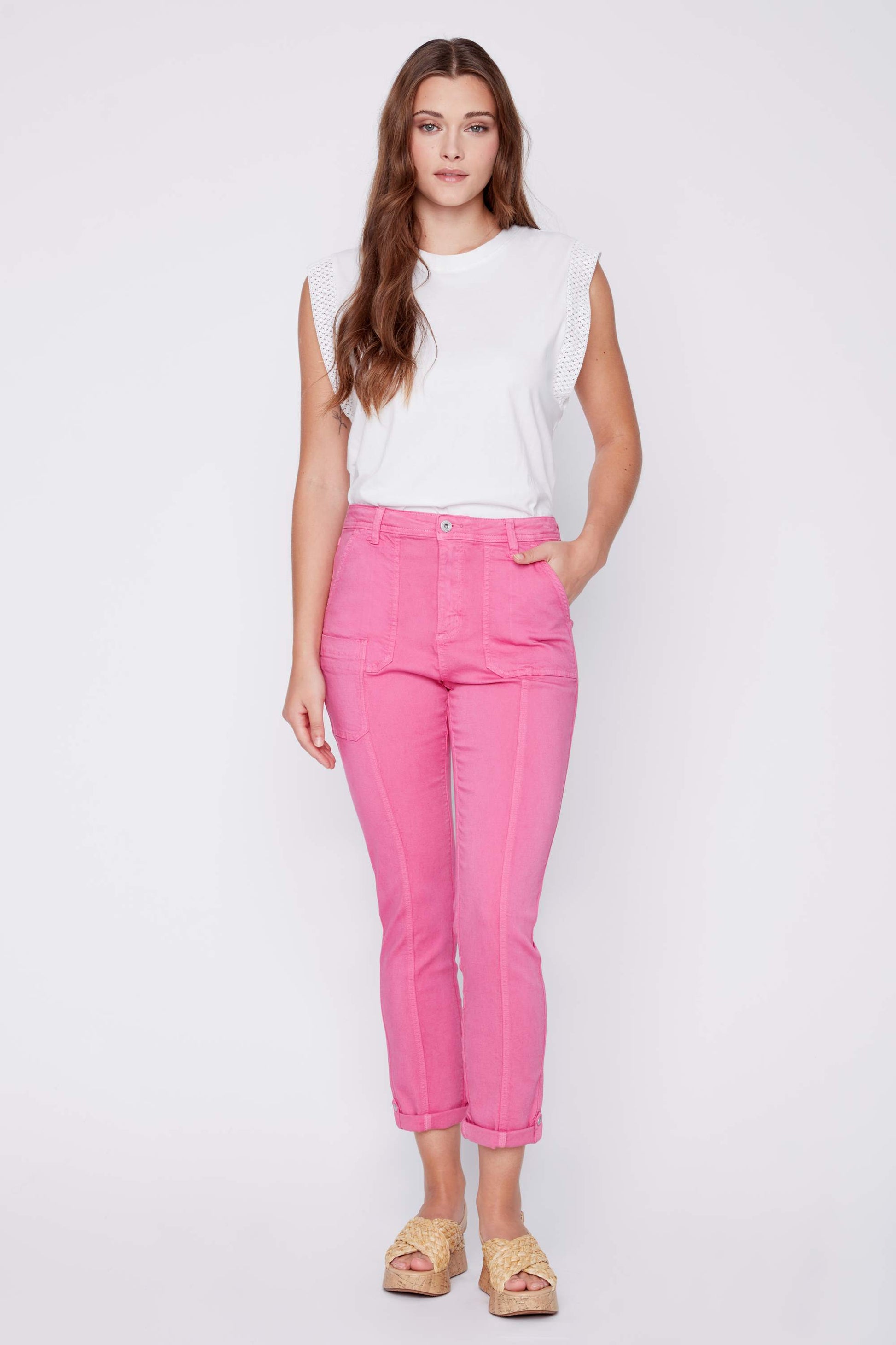 A woman standing against a plain background, wearing a floral print sleeveless top and chic beige CoCo Y Club Front Seam Crop Pants, with her hands slightly behind her.