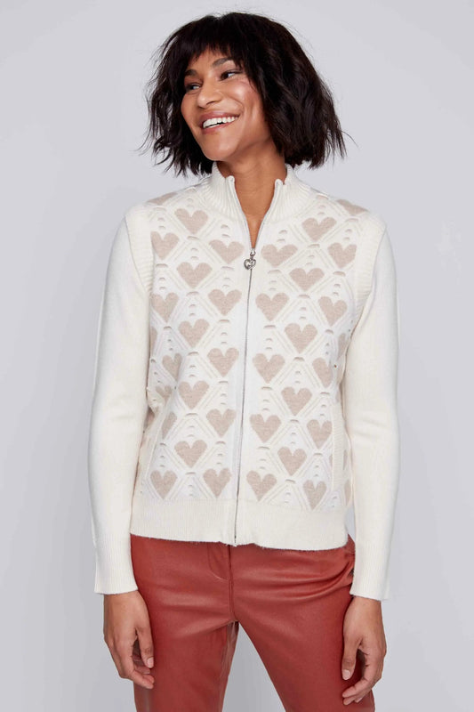 A person with shoulder-length dark hair is smiling and wearing a super soft, white CoCo Y Club Zip Up Cardigan with Hearts, paired with red pants.