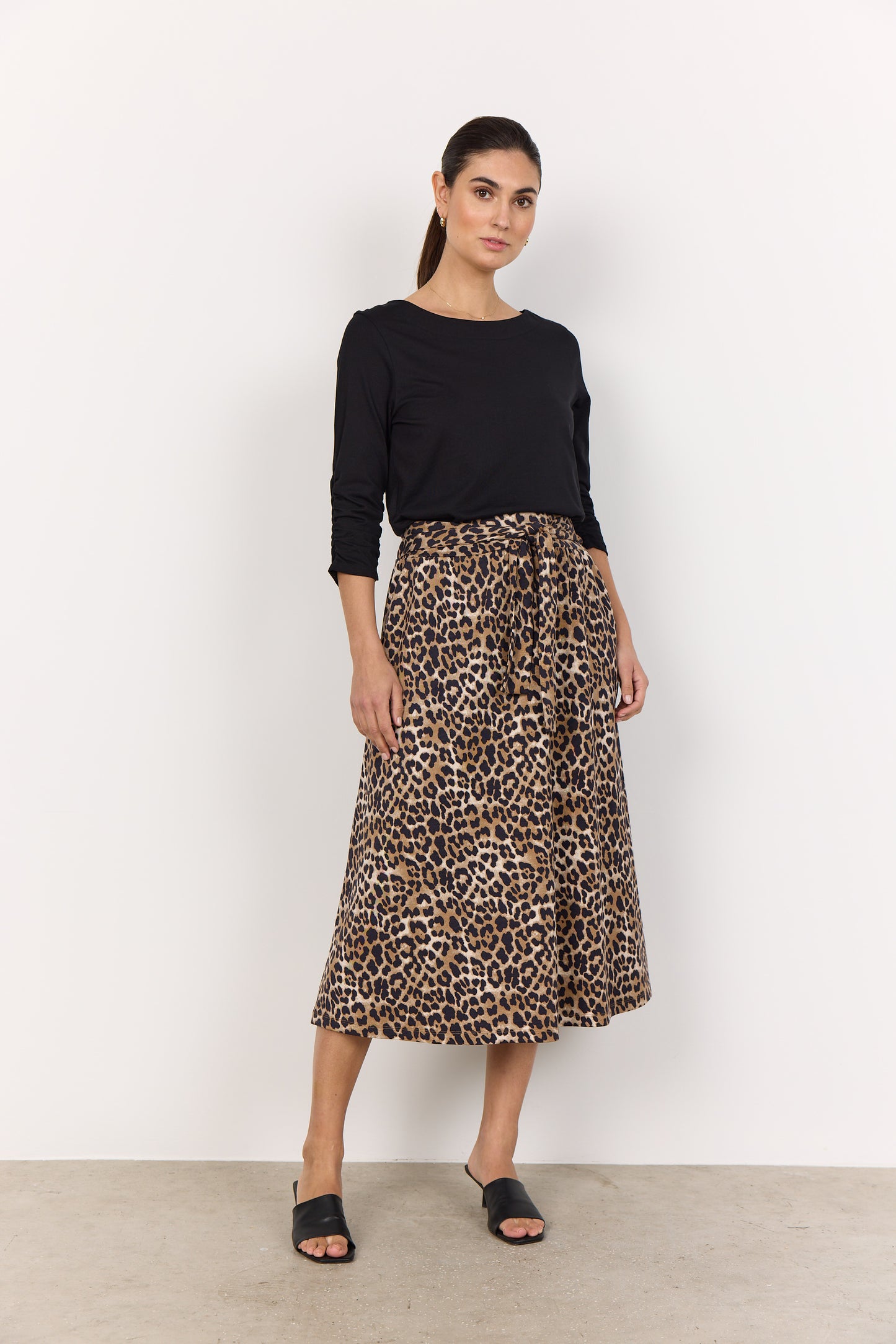 A woman in a Derby 44 Top from Soya Concepts and a leopard print skirt stands against a plain white background, showcasing a casual everyday look.