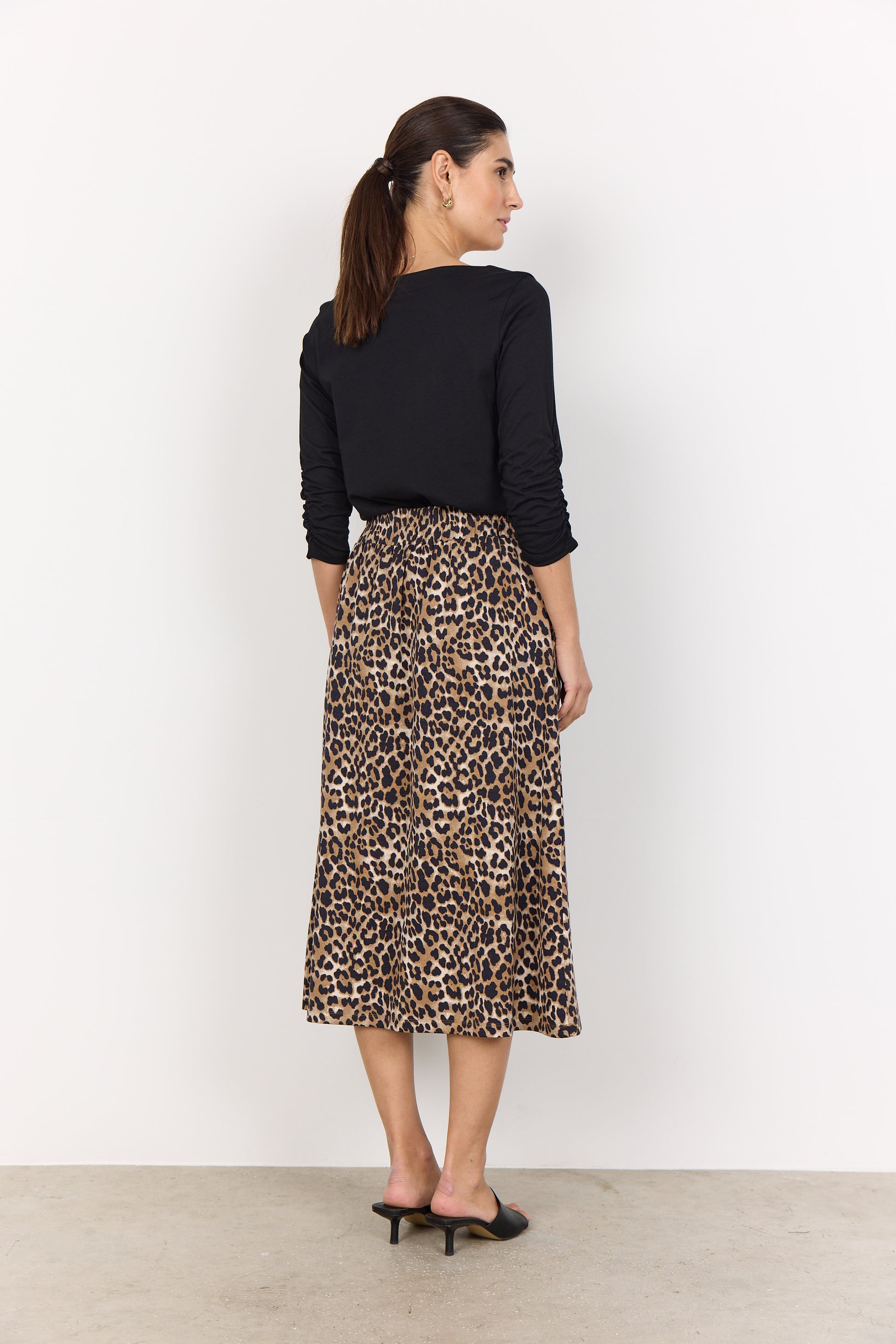 A woman in a Derby 44 Top from Soya Concepts and a leopard print skirt stands against a plain white background, showcasing a casual everyday look.