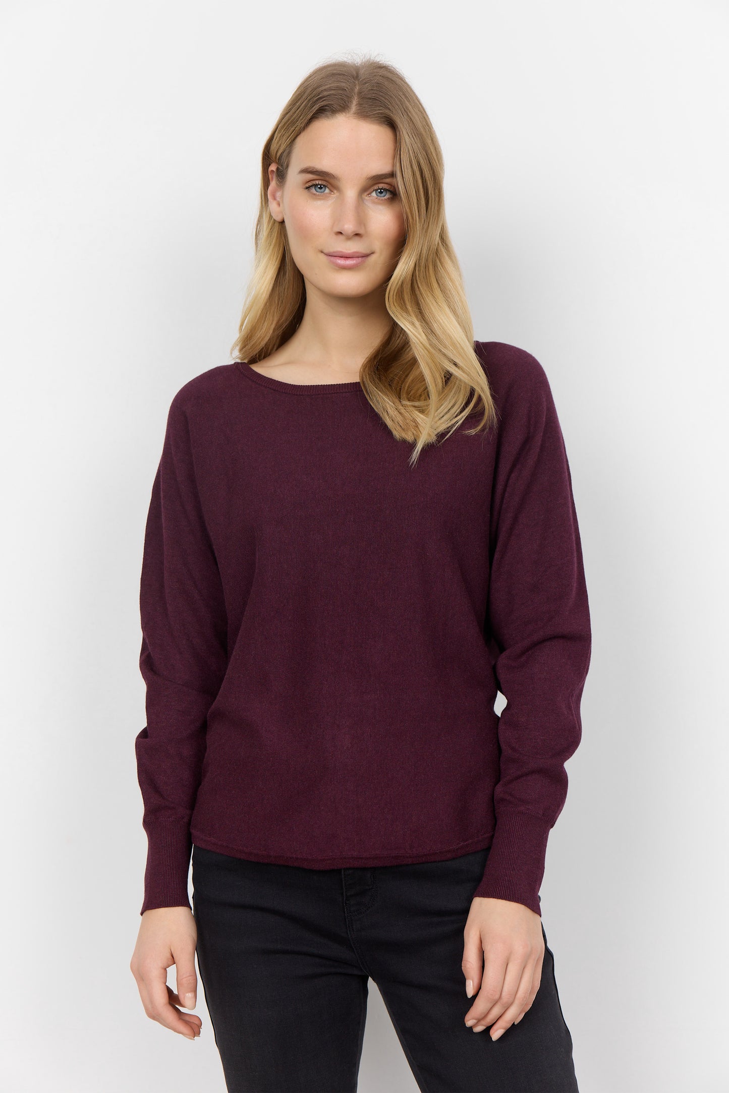 A person with long blond hair is wearing a comfortable Soya Concepts Dollie 620 Long Sleeve Sweater in maroon with button detail, paired with black pants, and is standing against a plain white background.