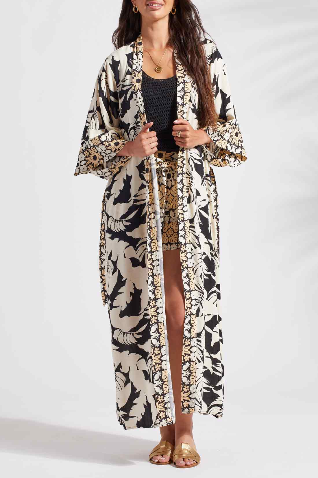 A woman wearing a Tribal 3/4 Sleeve Duster in Wailea kimono and shorts strikes the pose in black and white attire.