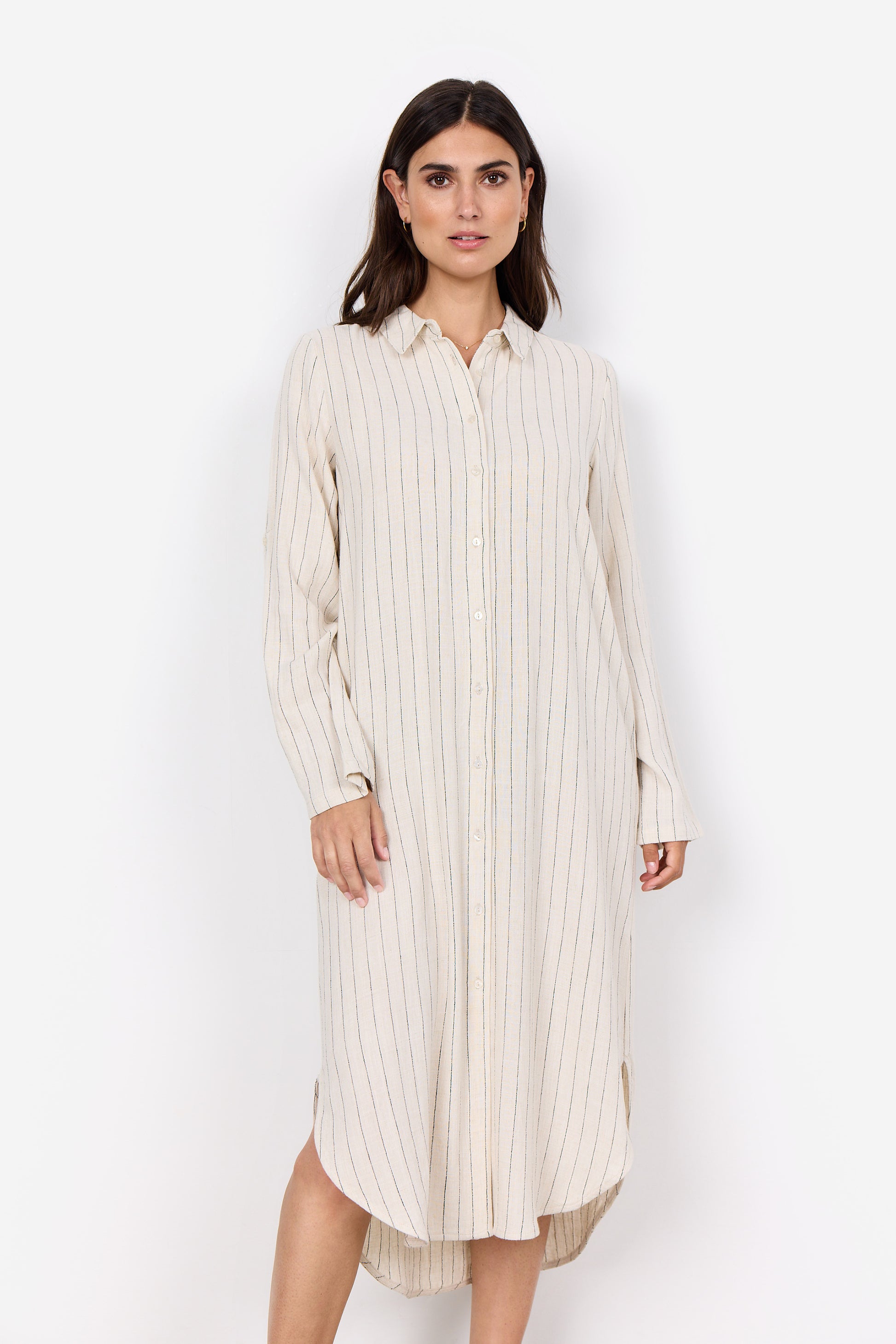 A woman stands against a plain white background, elegantly dressed in the Poula 4 Midi Dress by Soya Concepts, made from ECOVERO Viscose and featuring cream-colored vertical stripes with buttons down the front.