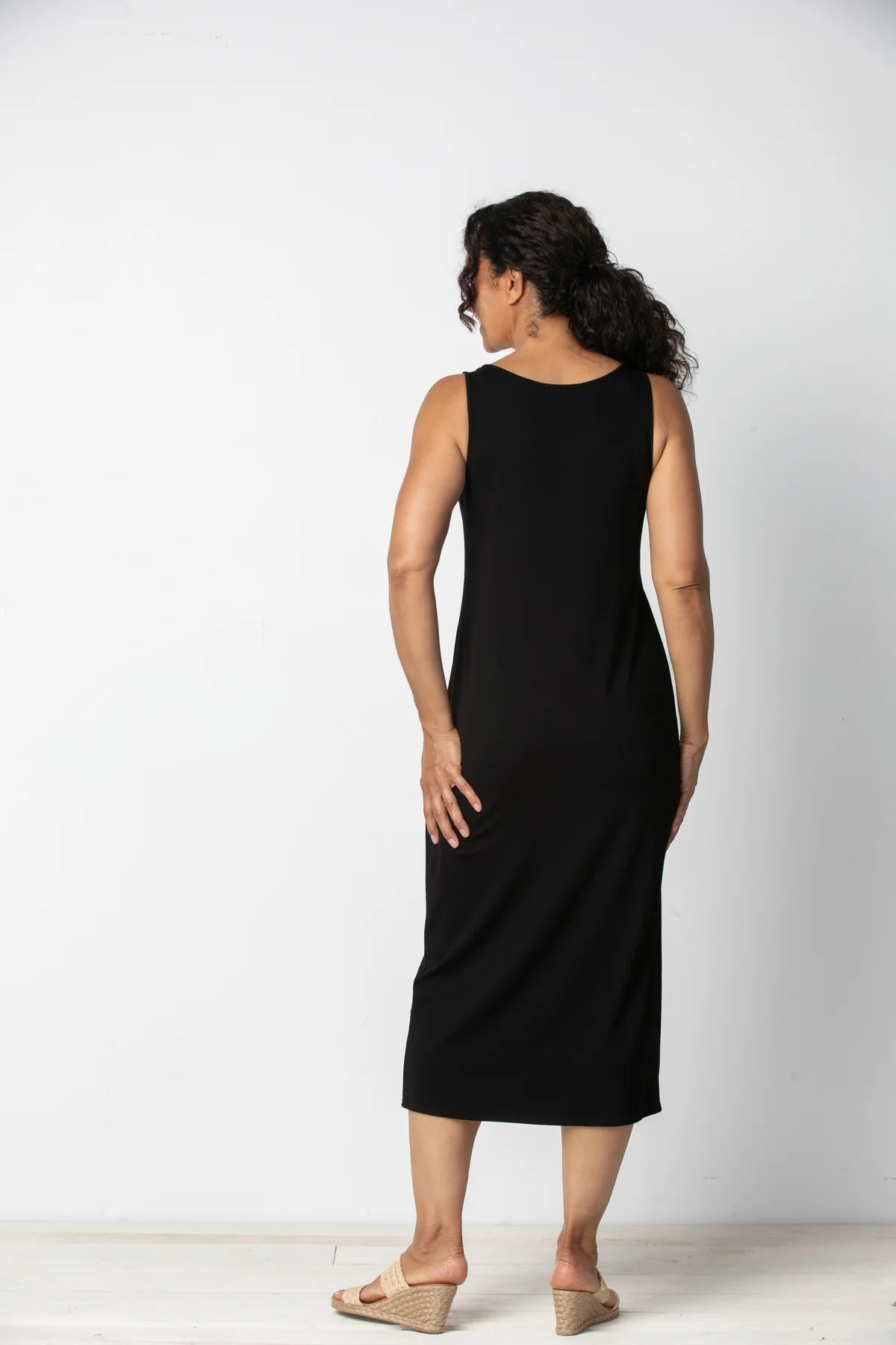 Smiling woman standing in a Habitat Sleeveless Black Everything Dress against a white background.