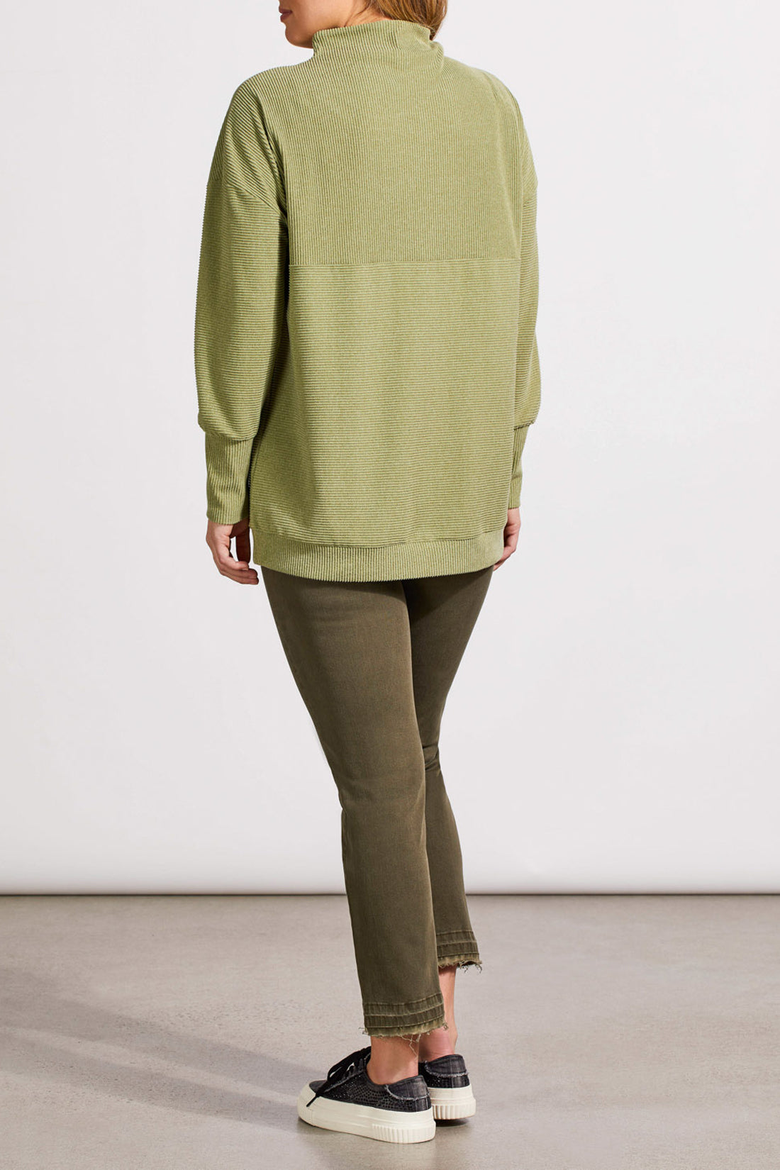 A person wearing a light green, long-sleeved knit sweater and green pants stands against a plain white background. The comfortable outfit includes the Funnel Neck Tunic by Tribal, which adds an extra touch of style.