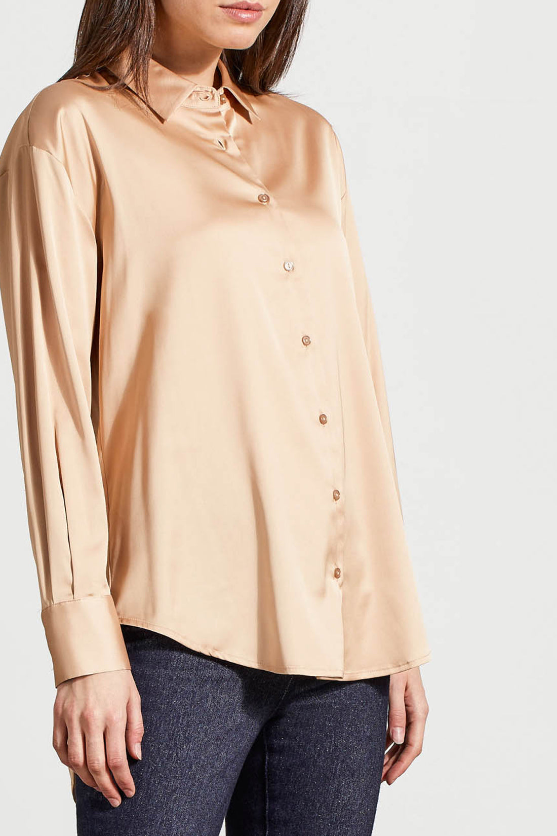 A person dressed in a cozy fall top, specifically the beige Drop Shoulder Shirt by Tribal with silk fabric, pairs it effortlessly with dark jeans against a light background.