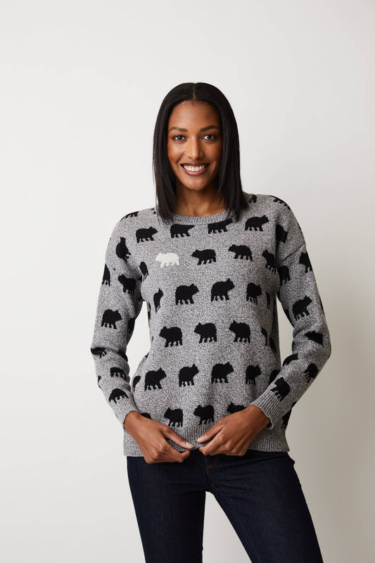 A woman smiles confidently with hands on her hips in a gray Parkhurst Bear Naked Sweater, featuring black bear patterns and one standout white bear, showcasing the fashion-forward outdoors enthusiast vibe against a plain background.