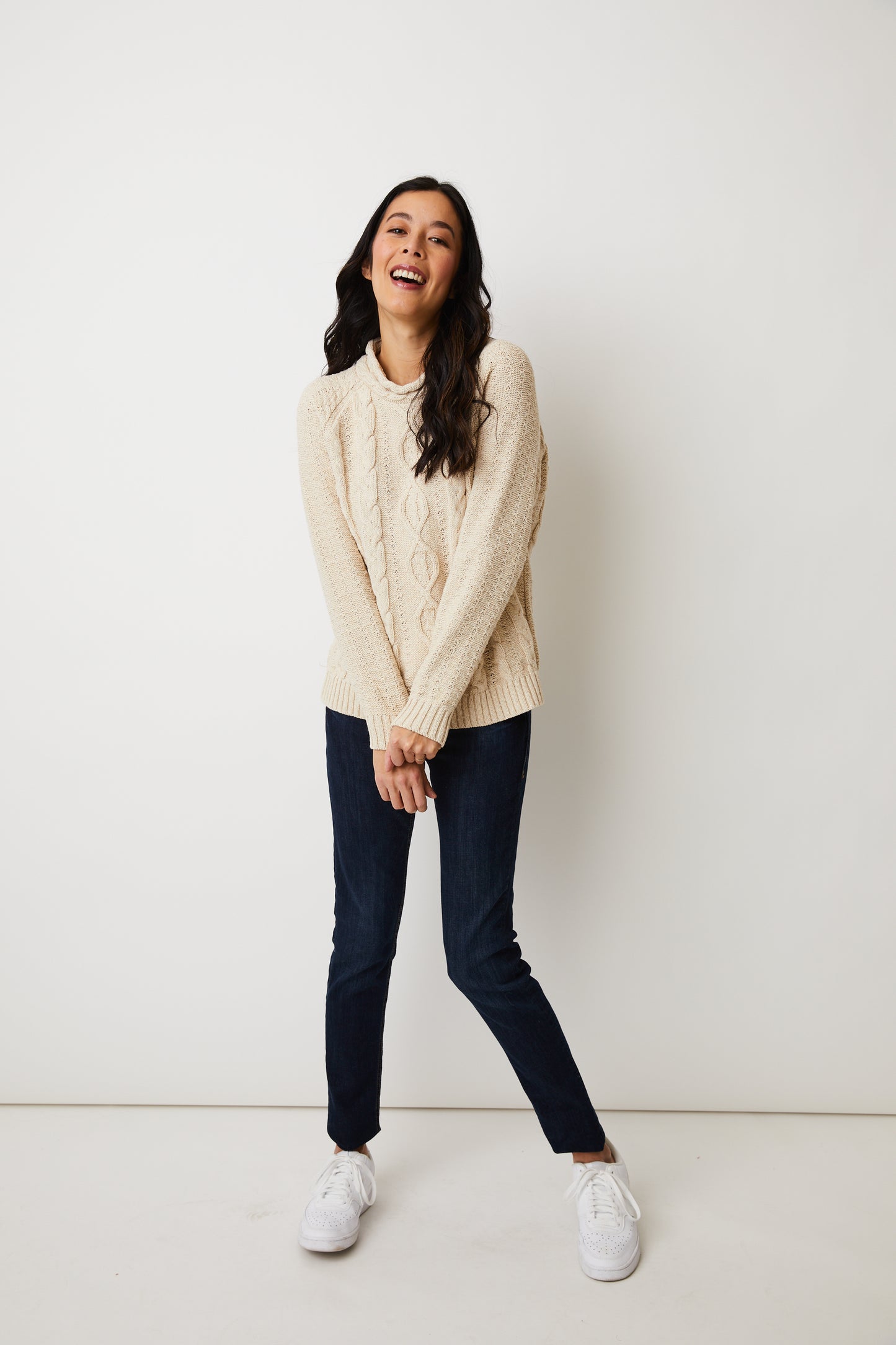 Parkhurst Samira Sweater- A woman wearing a cozy beige sweater and a pom pom hat.