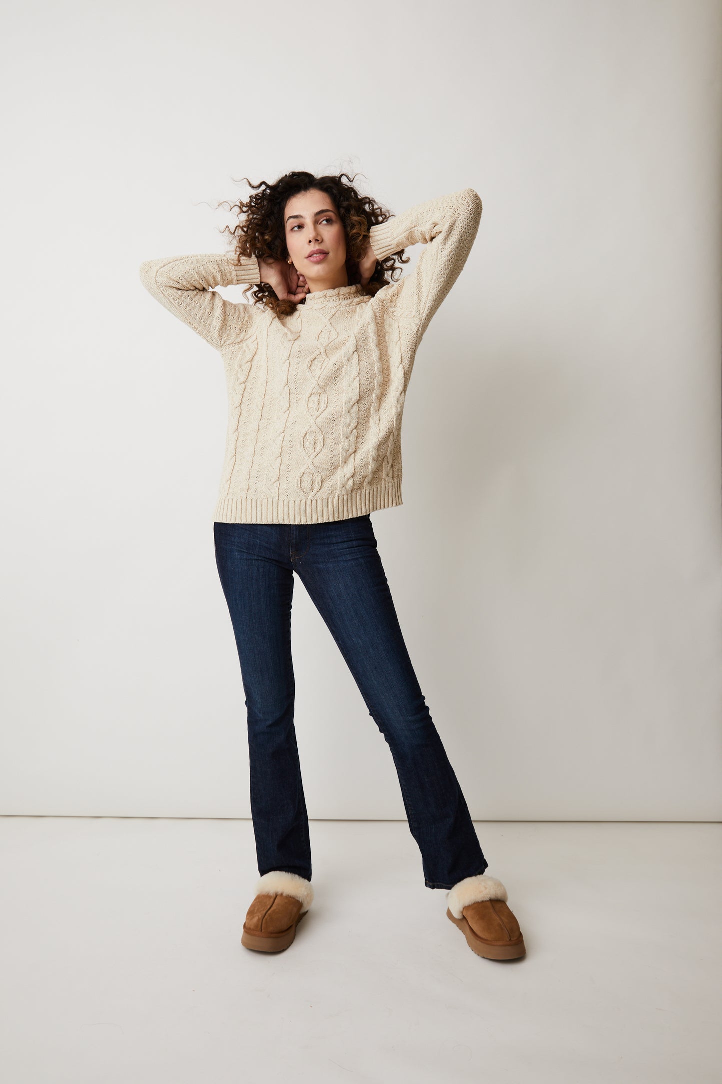 Parkhurst Samira Sweater- A woman wearing a cozy beige sweater and a pom pom hat.