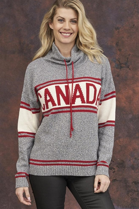 A person smiles while wearing a Cotton Country Canada Pullover Sweater, featuring red "CANADA" lettering on the chest, against a mottled brown backdrop.