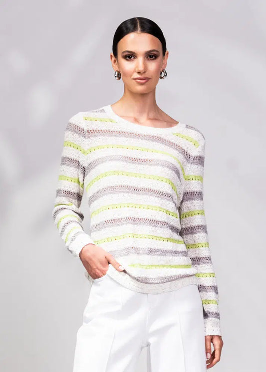 A person is wrapped in an Alison Sheri Striped Knit Sweater with green and white stripes, perfectly paired with white pants. The plain light gray background enhances the outfit's versatile and trendy appeal.