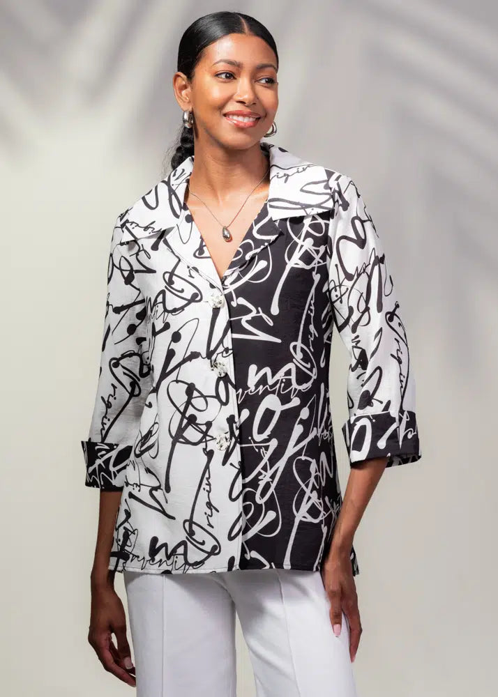 A person gracefully stands against a shadowed neutral background wearing an Alison Sheri Abstract Print Jacket in a stylish black and white monochrome design paired with white pants.