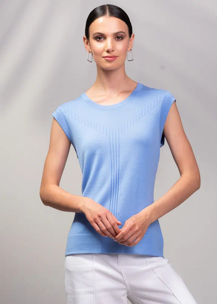 A person wearing an Alison Sheri light blue Round Neck Sleeveless Top and white pants stands against a neutral background, accessorized with hoop earrings and a neutral expression.