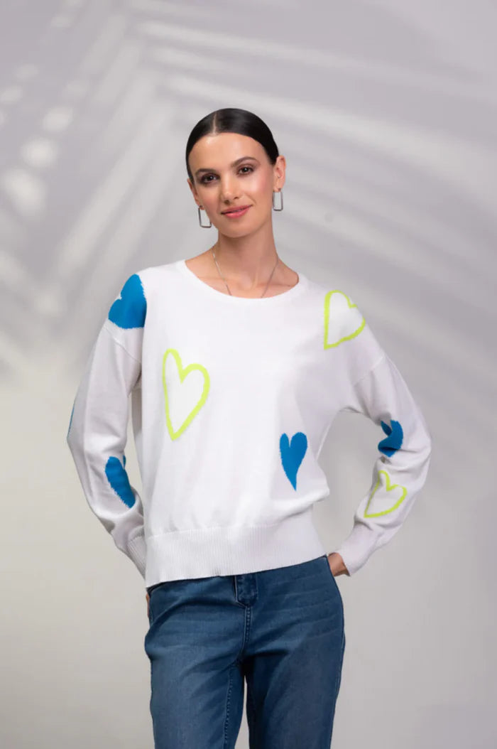 Someone wearing a chic Blue Heart Sweater by Alison Sheri, featuring long sleeves with blue and yellow heart patterns, paired with blue jeans.