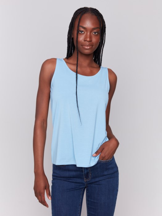 A person wearing a Charlie B Reversible Bamboo Viscose Cami and dark blue jeans stands against a plain gray background.