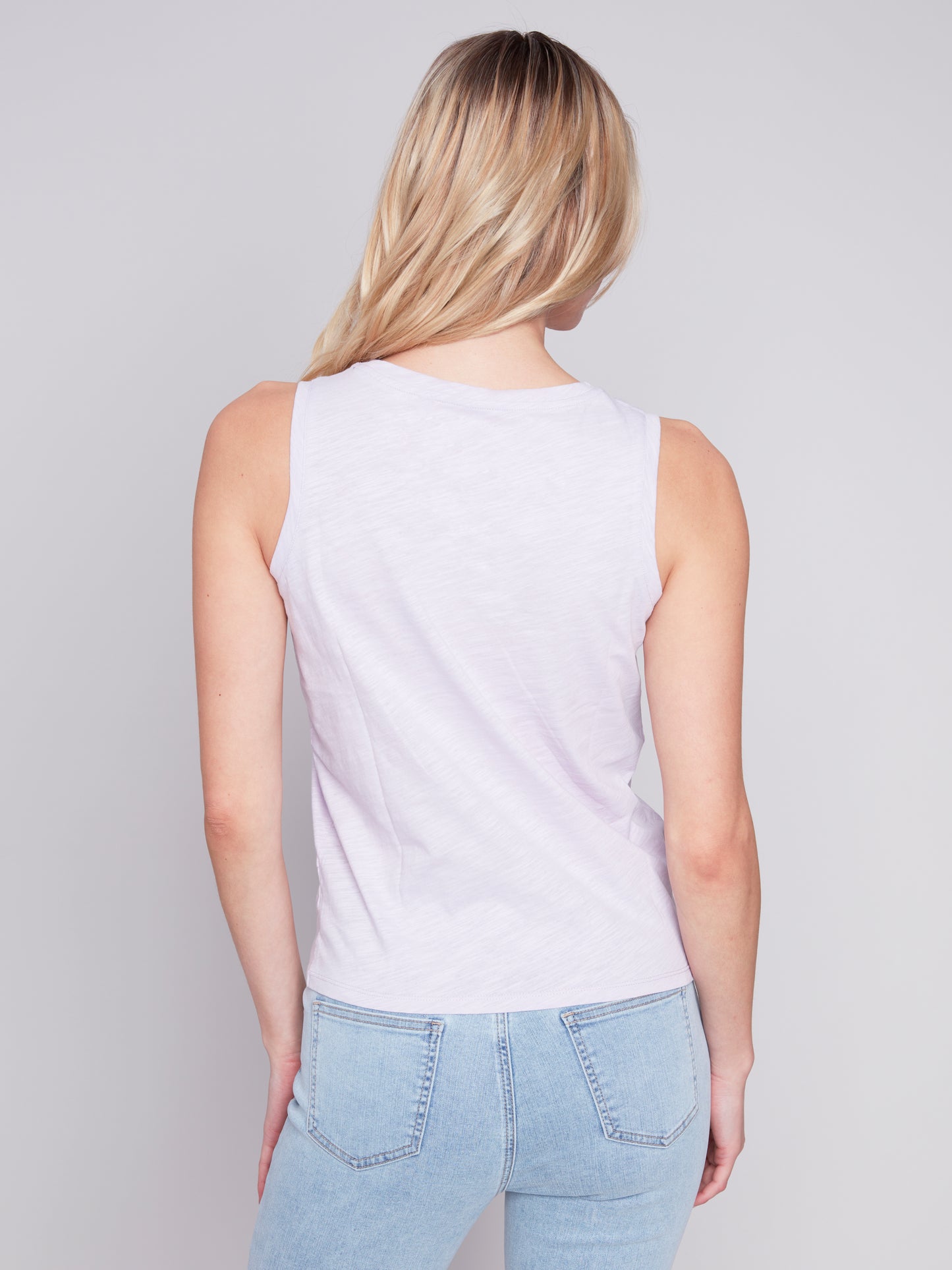 Woman in versatile, high-quality Charlie B crew neck tank tops and casual sportswear posing against a gray background.