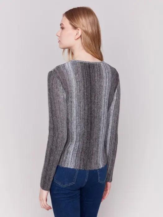 A person with long hair wearing a cozy Space Dye Yarn Crop Sweater by Charlie B and blue jeans stands against a plain background.