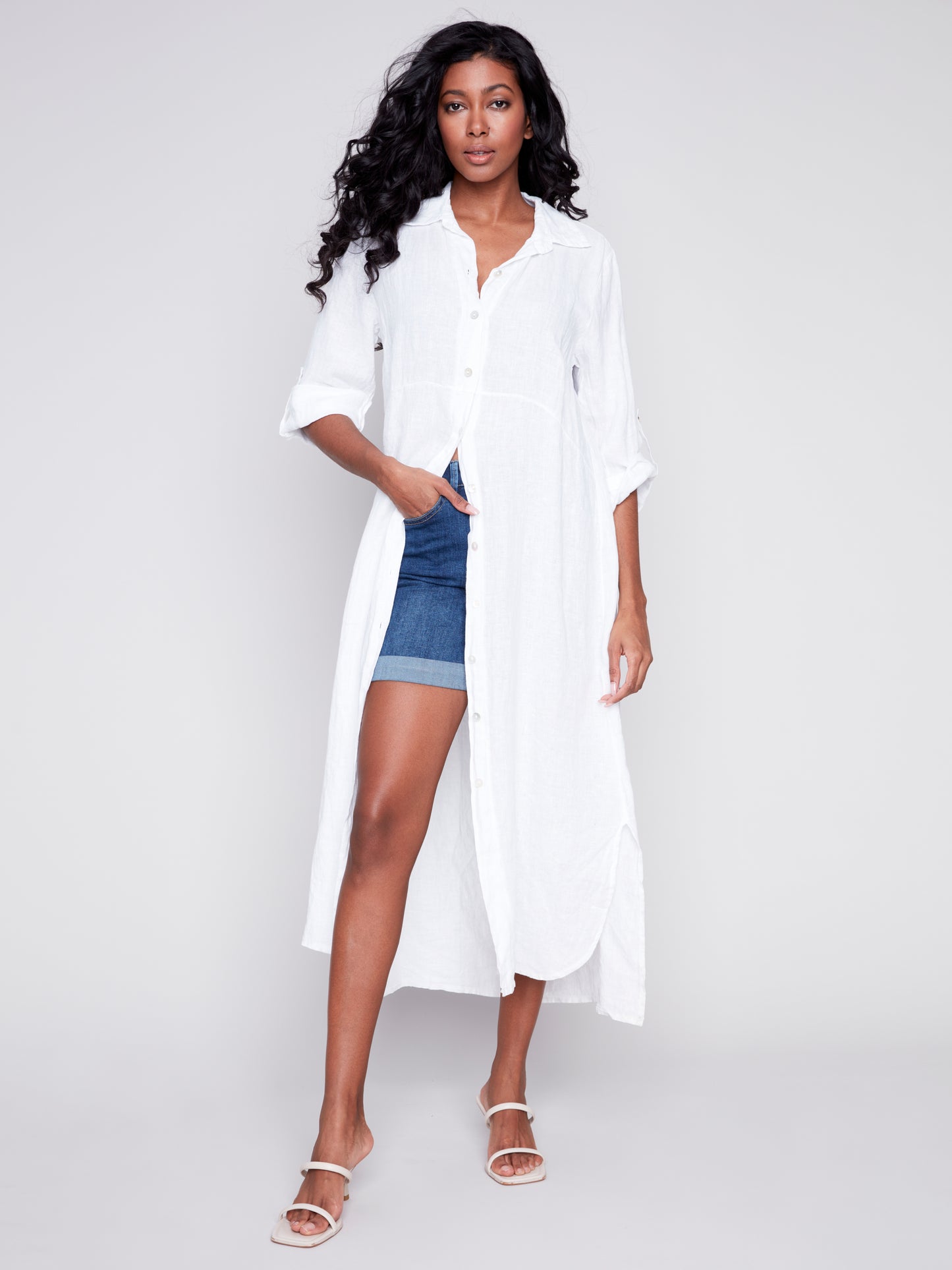 The model is wearing a white Charlie B duster with rolled-up sleeves and denim shorts.
