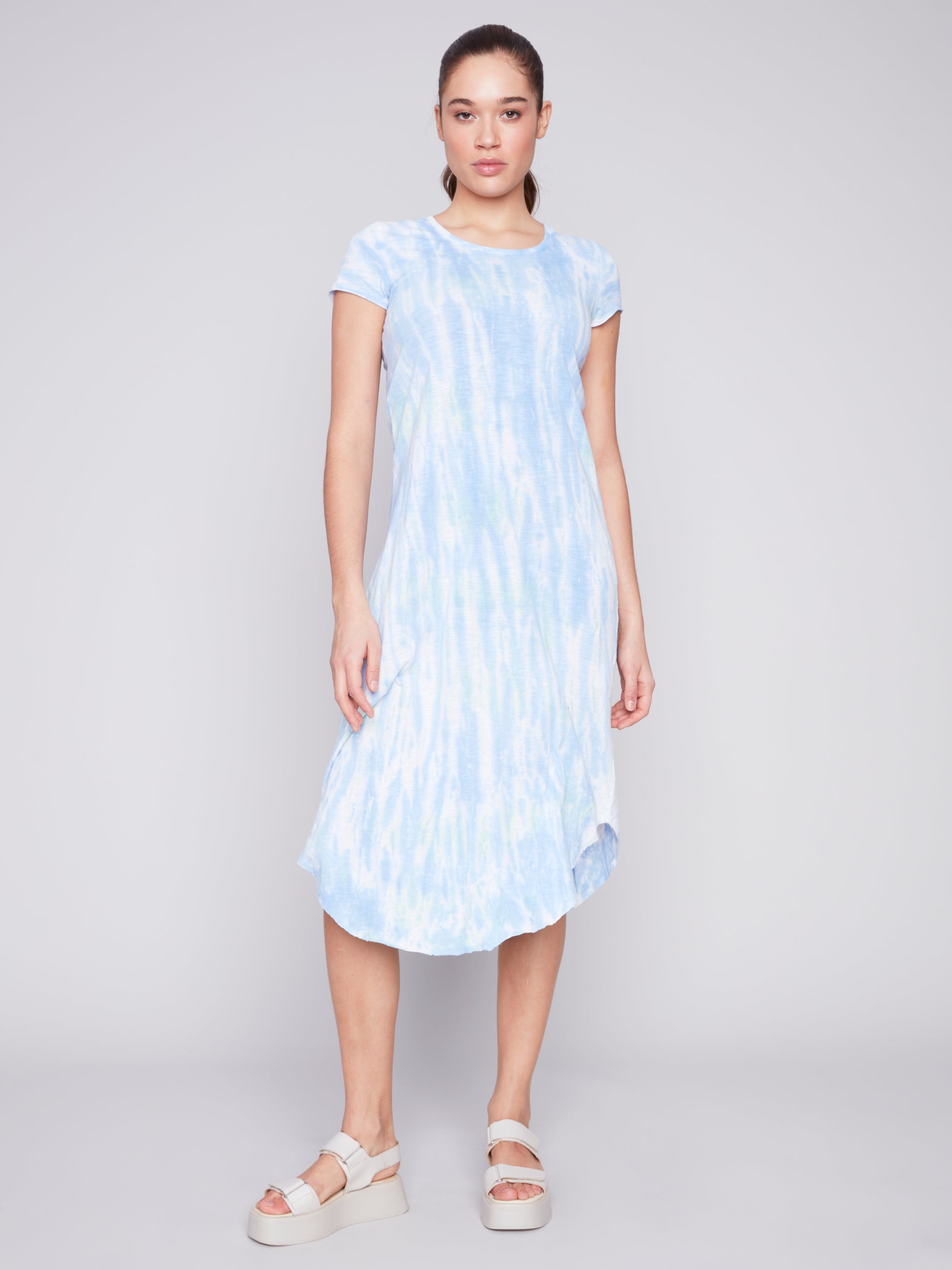 A woman wearing a Charlie B Ocean Wind Short Sleeve Dress, a high-quality fabric blue and white tie-dye summer dress with short sleeves, standing in a neutral pose against a grey background.