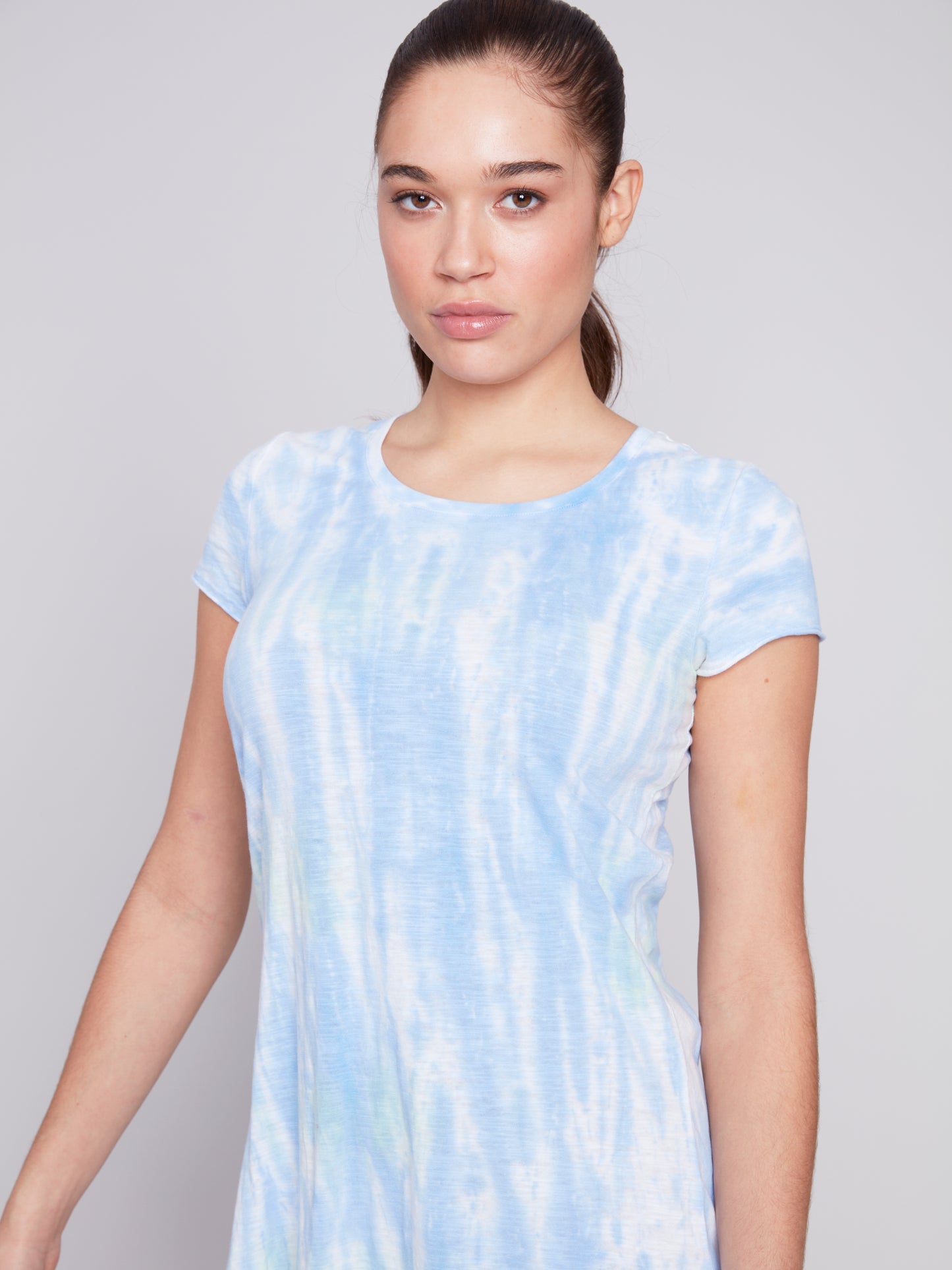 A woman wearing a Charlie B Ocean Wind Short Sleeve Dress, a high-quality fabric blue and white tie-dye summer dress with short sleeves, standing in a neutral pose against a grey background.