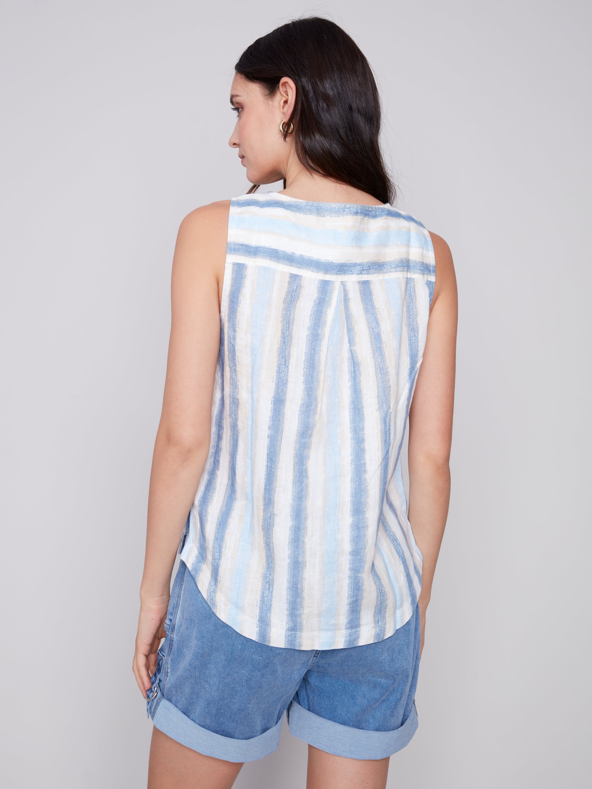 The model is wearing a stylish Charlie B Linen Top with Side Buttons in blue stripes.