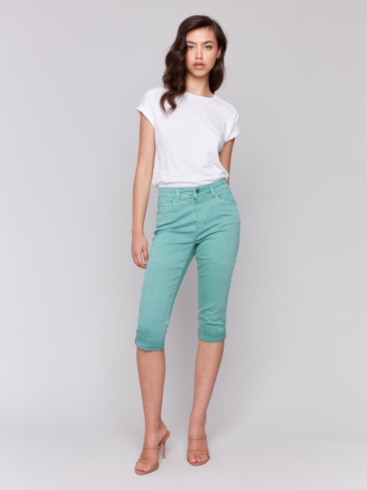 Someone wearing Charlie B's stylish turquoise Stretch Twill Pedal Pusher Pants with rolled cuffs and a crisp white top stands against a plain background.