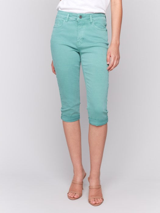 Someone wearing Charlie B's stylish turquoise Stretch Twill Pedal Pusher Pants with rolled cuffs and a crisp white top stands against a plain background.