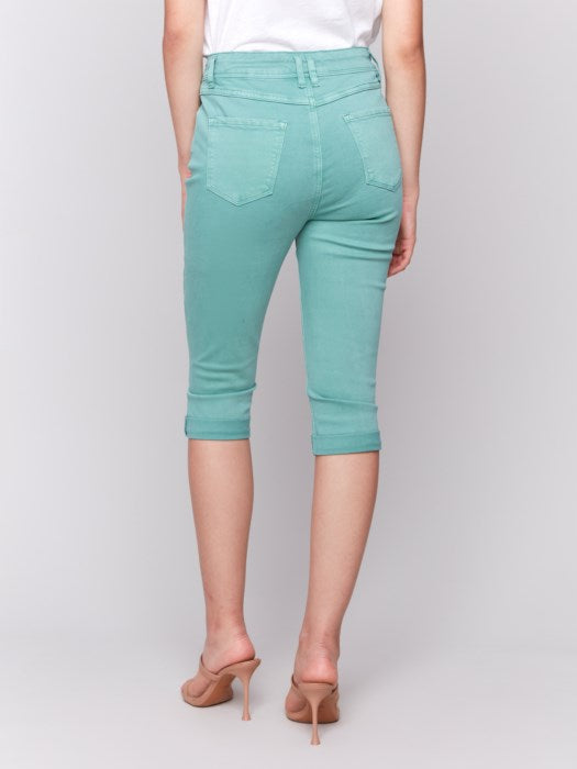 Someone wearing Charlie B's stylish turquoise Stretch Twill Pedal Pusher Pants with rolled cuffs and a crisp white top stands against a plain background.