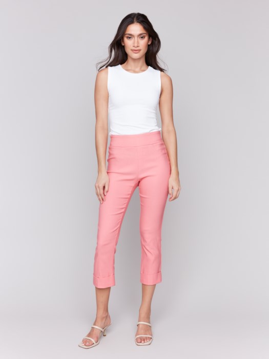 Rear view of someone wearing flattering pink Stretch Pull-On Capri Pants by Charlie B and a white top, standing in heels against a neutral background.