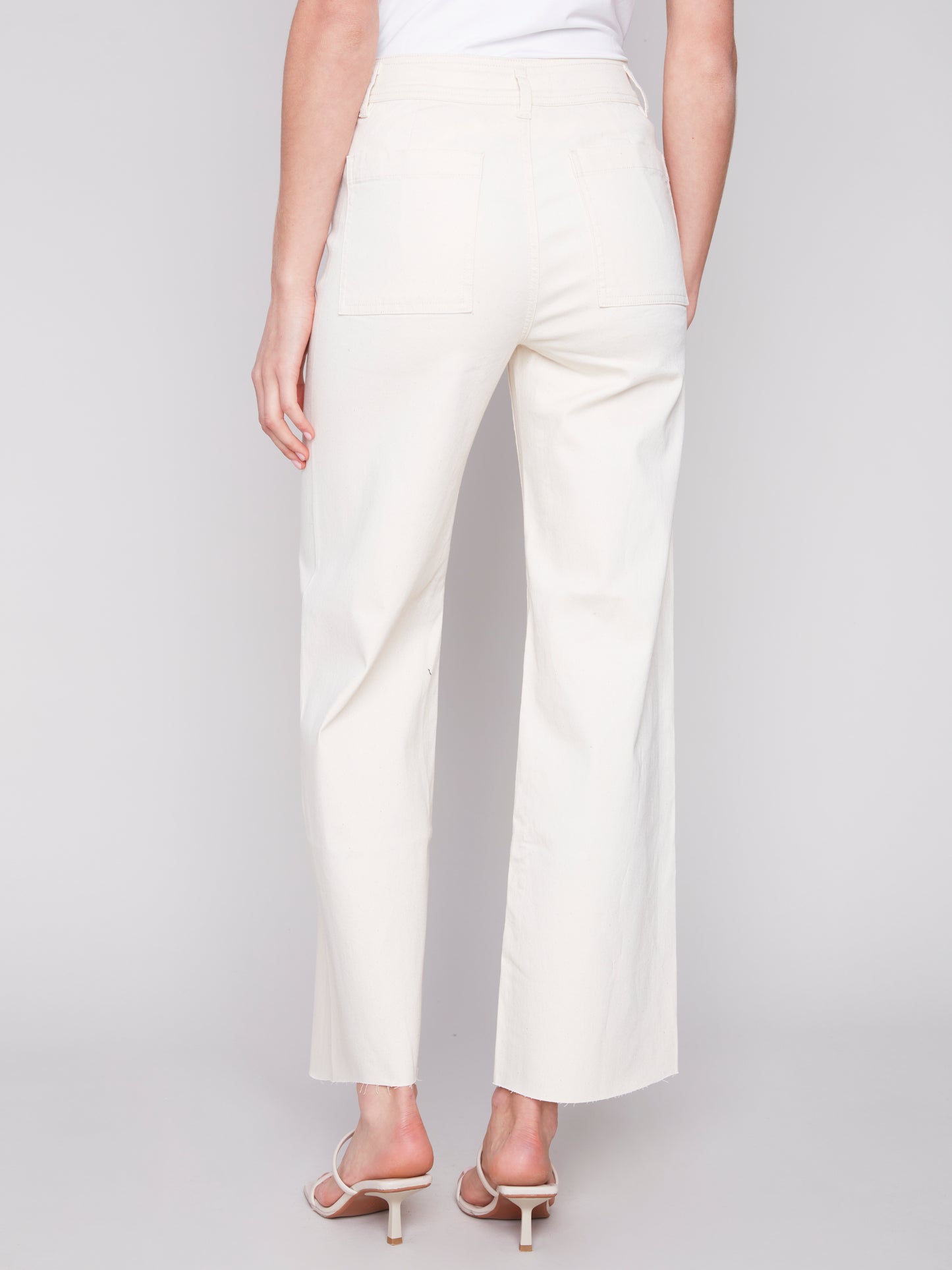 A woman wearing Charlie B cream natural wide leg pants made from lightweight fabric.