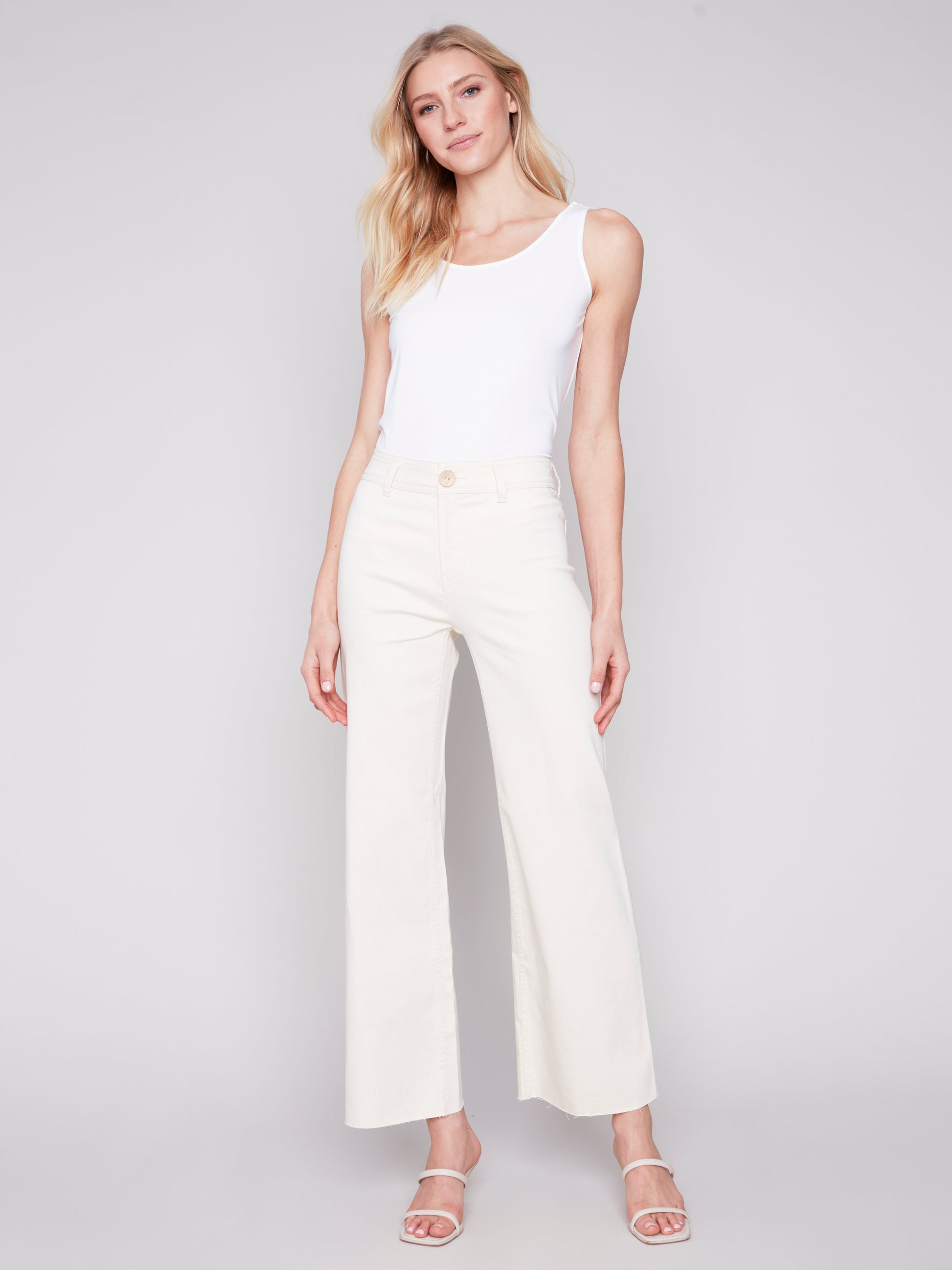 A woman wearing Charlie B cream natural wide leg pants made from lightweight fabric.