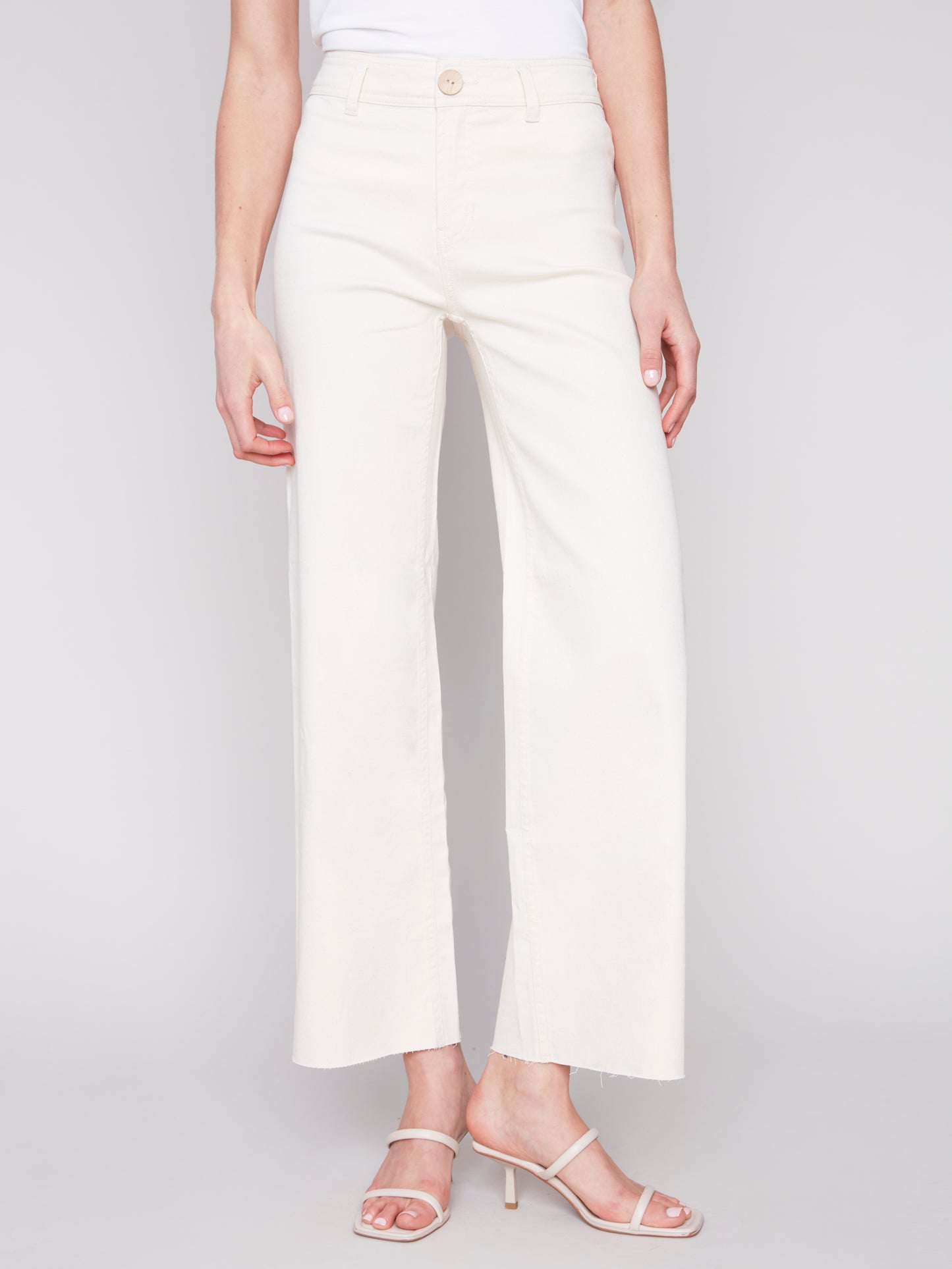 A woman wearing Charlie B cream natural wide leg pants made from lightweight fabric.