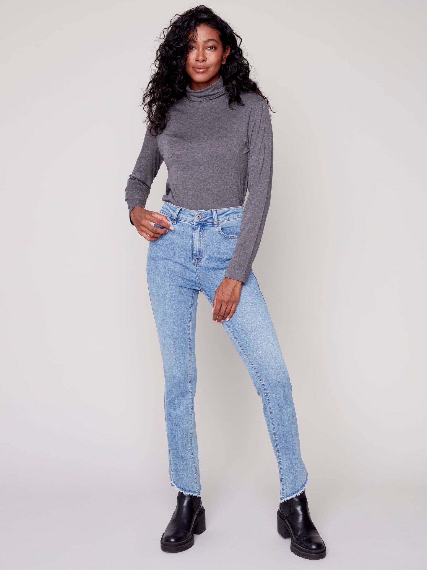 A woman in Charlie B's asymmetrical hem bootcut jeans and black Chelsea boots creates a flattering look.