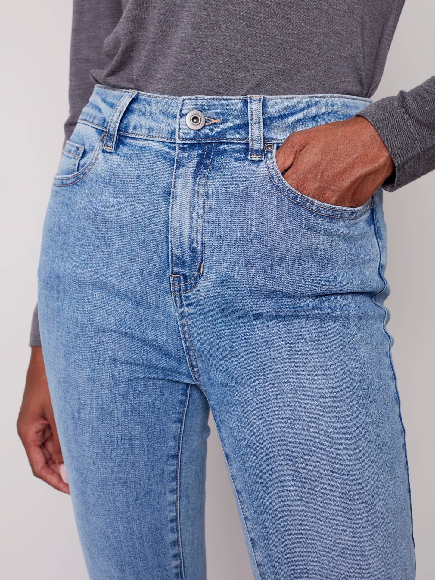 A woman in Charlie B's asymmetrical hem bootcut jeans and black Chelsea boots creates a flattering look.