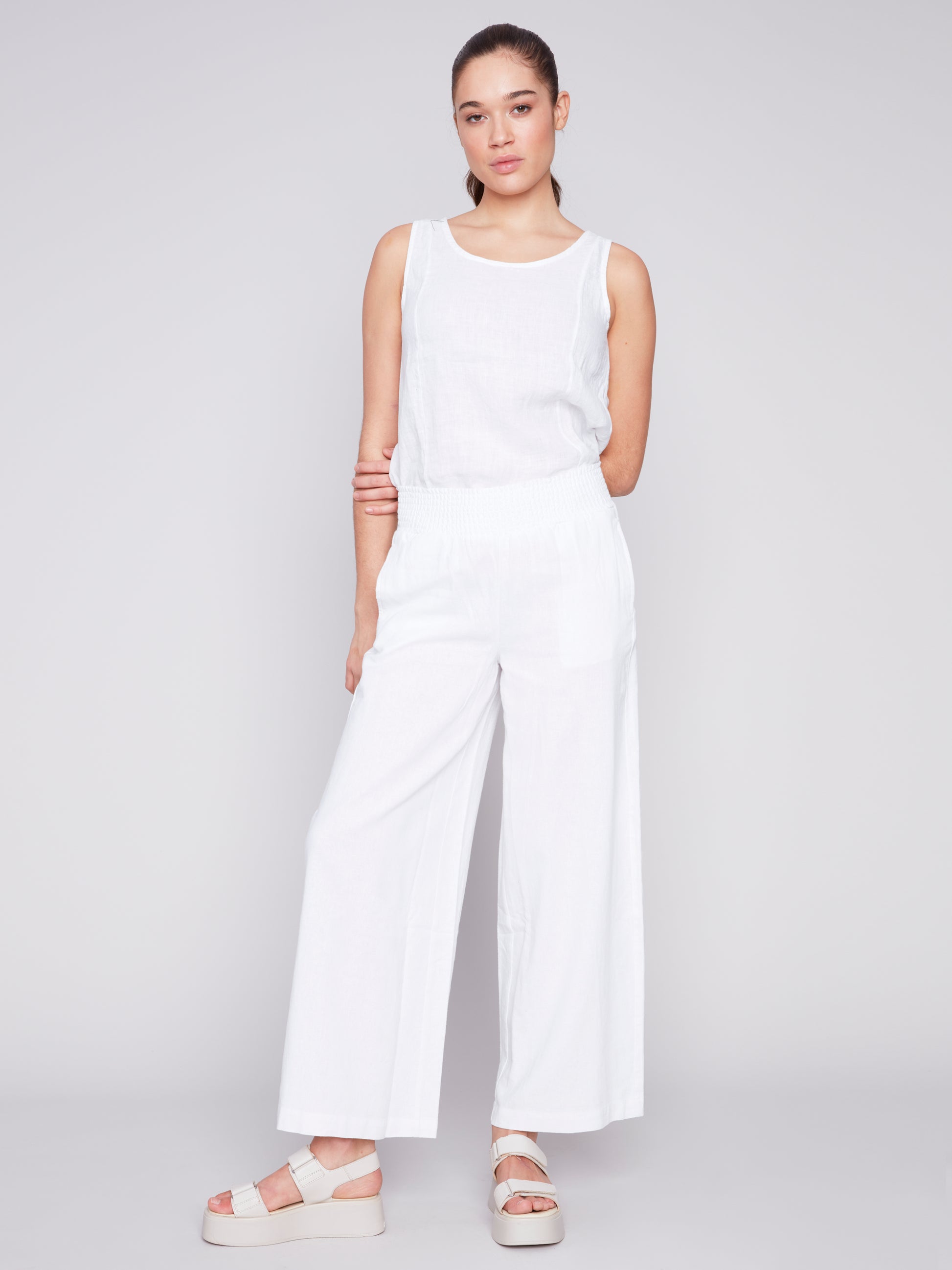 A fashion-forward woman elegantly donning Charlie B's Wide Leg Pull On Pant with Elastic Waist and sandals.