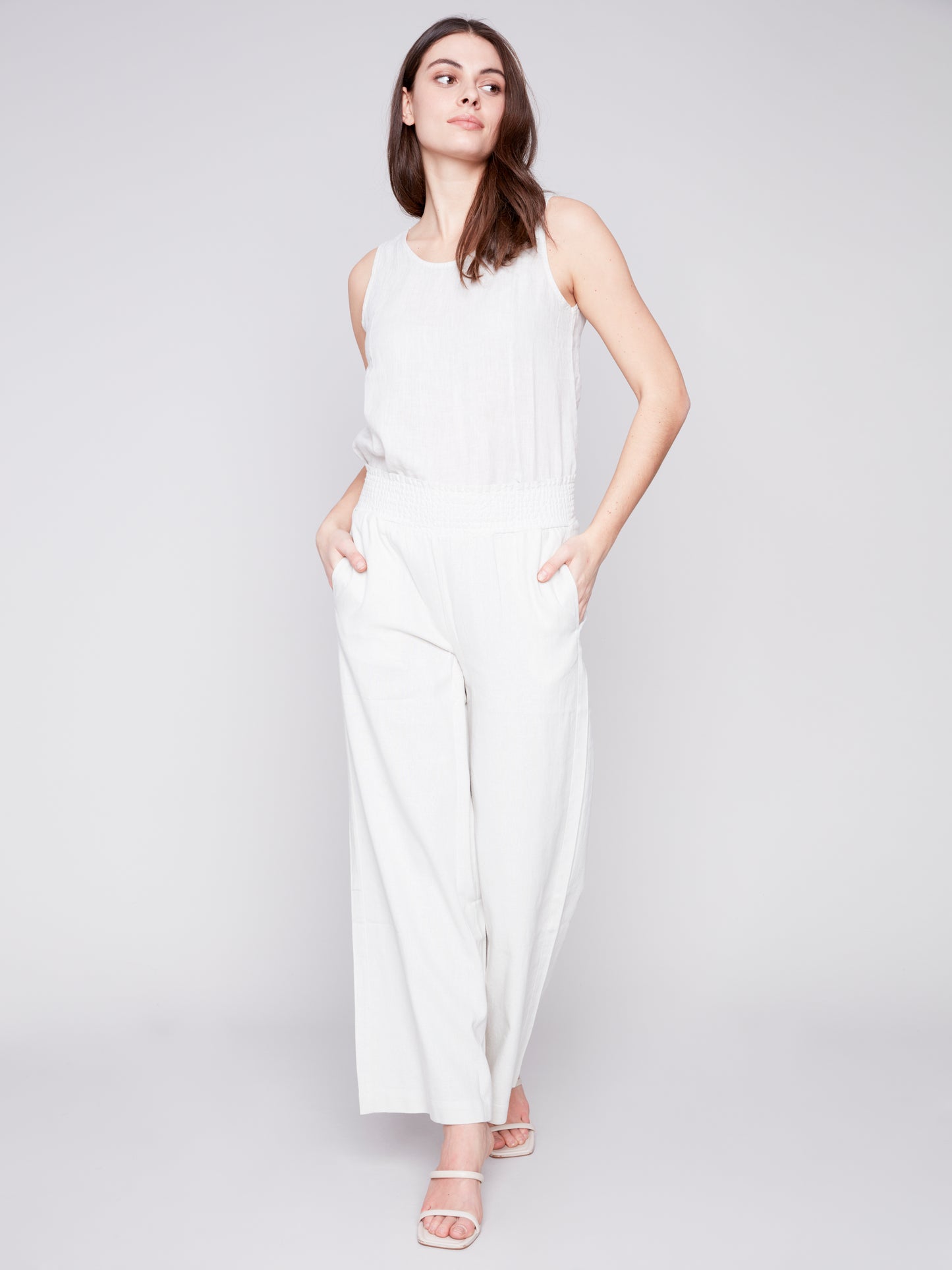 A fashion-forward woman elegantly donning Charlie B's Wide Leg Pull On Pant with Elastic Waist and sandals.