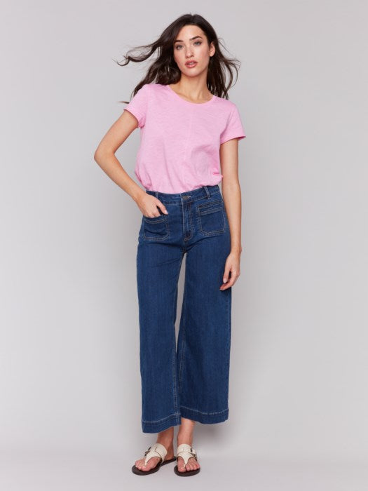 A person is expressing their style in Charlie B Patch Pocket Flare Jeans, paired with a pink top and sandals.