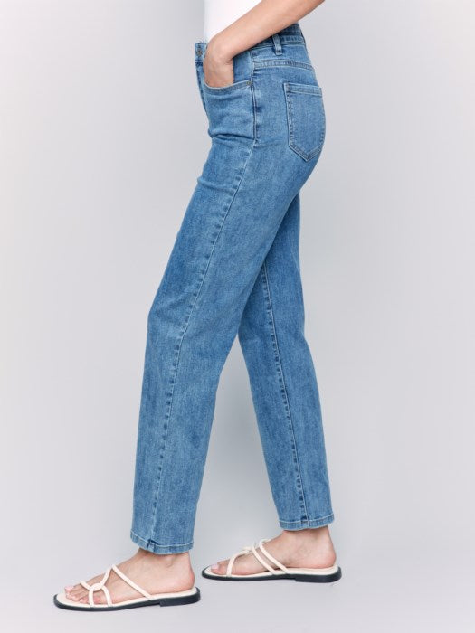 A person wearing Charlotte Straight Leg blue jeans by Charlie B and white sandals, photographed from the back, with a white top tucked for effortless style and comfort.