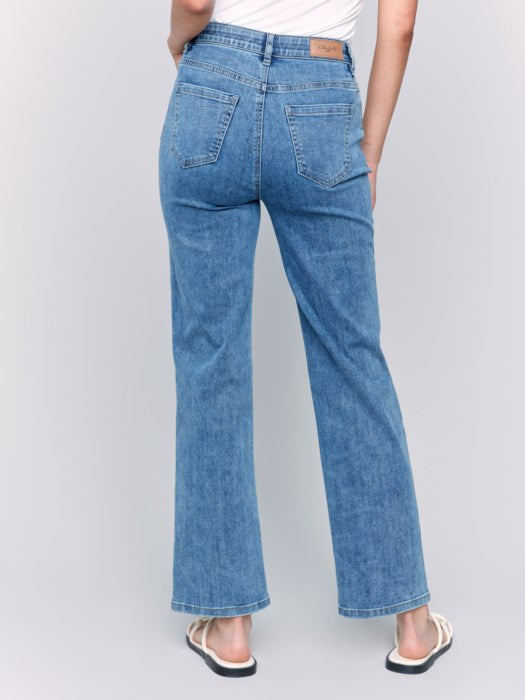 A person wearing Charlotte Straight Leg blue jeans by Charlie B and white sandals, photographed from the back, with a white top tucked for effortless style and comfort.