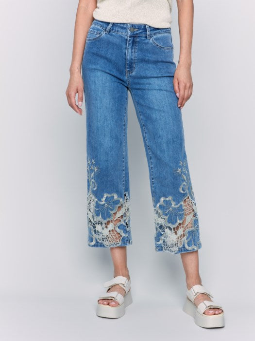 A woman is wearing Charlie B's Crop Flare Leg Jeans with a laser cut lace hem, paired with white platform sandals.