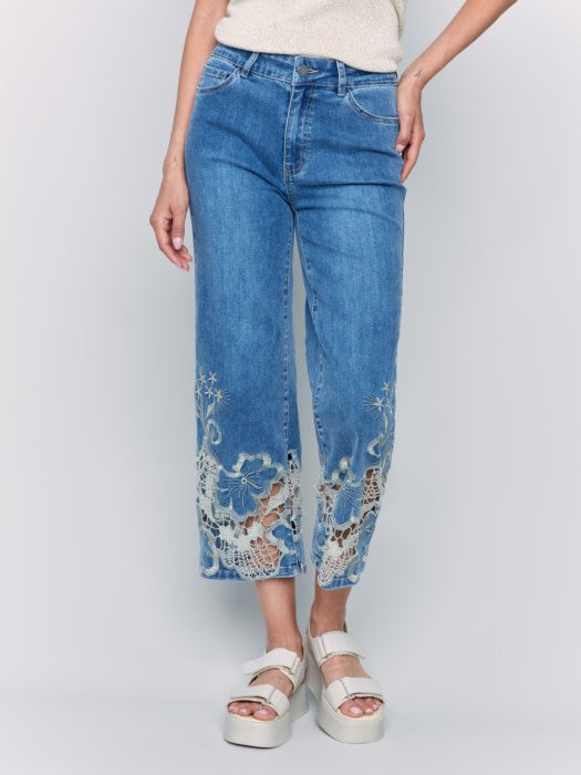 A woman is wearing Charlie B's Crop Flare Leg Jeans with a laser cut lace hem, paired with white platform sandals.