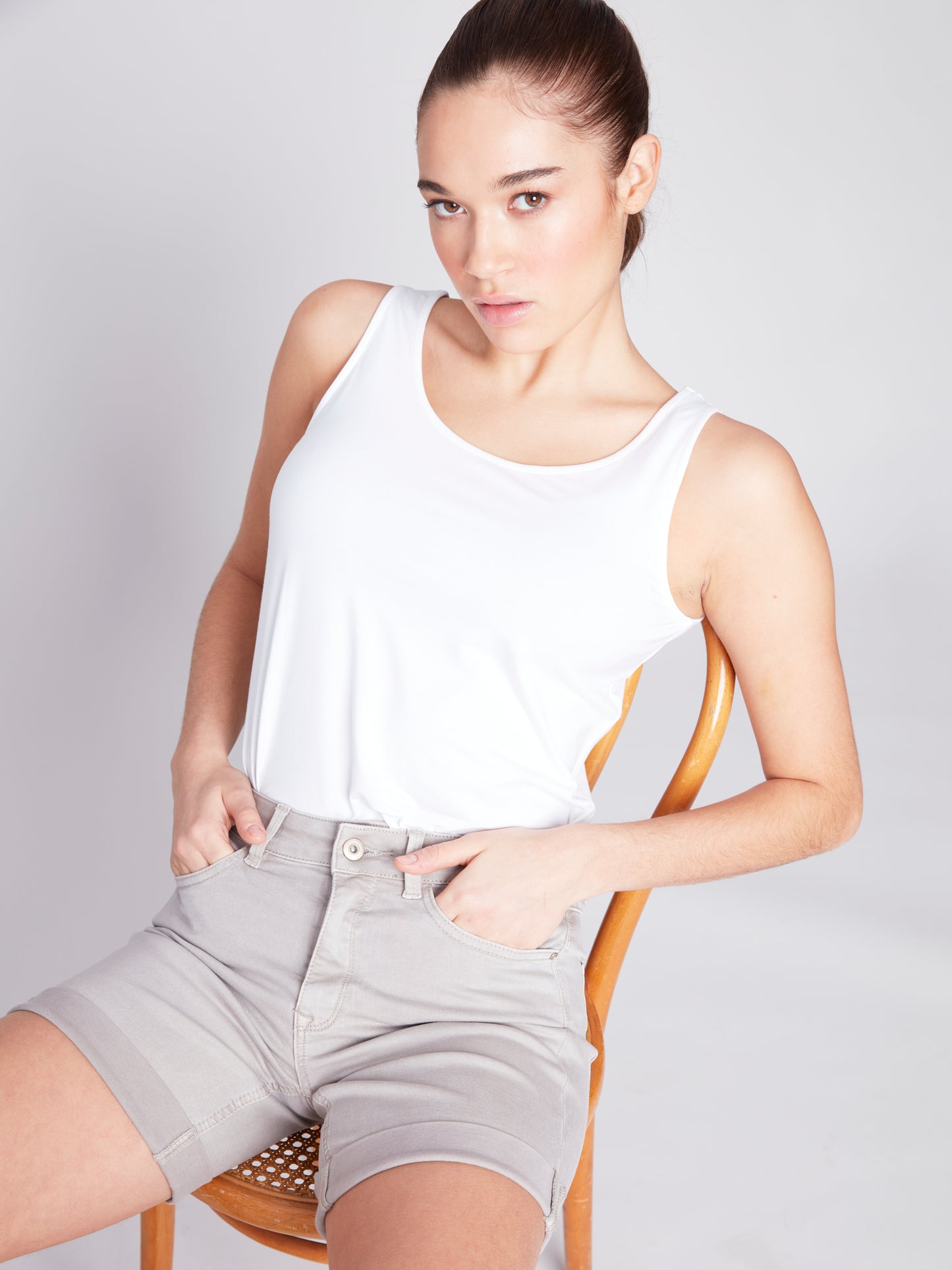 The model is wearing a white tank top and versatile Charlie B Rolled Up Cuff Shorts.